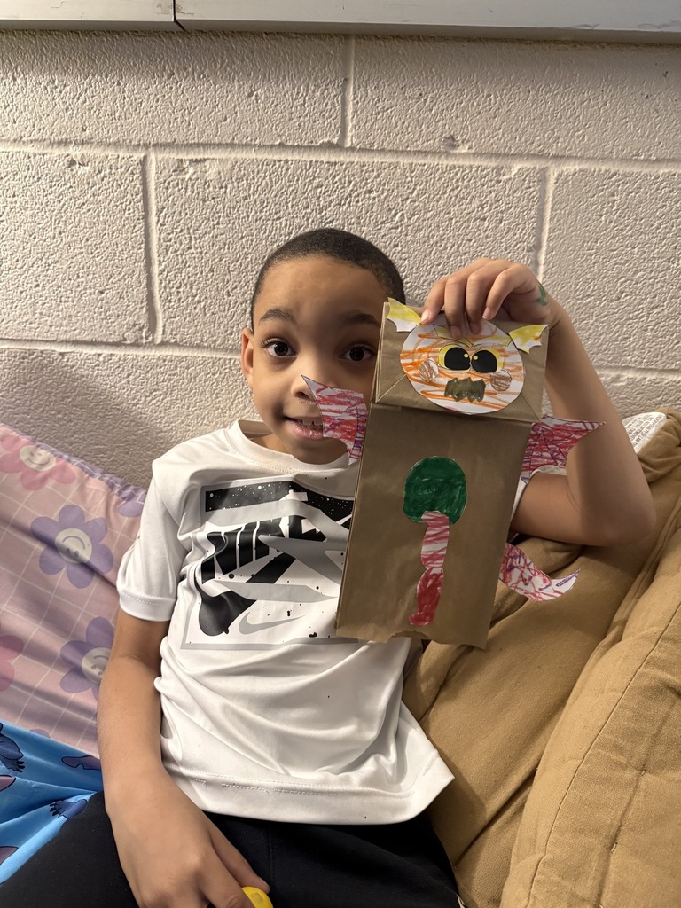 Young boy holding his dragon puppet up.