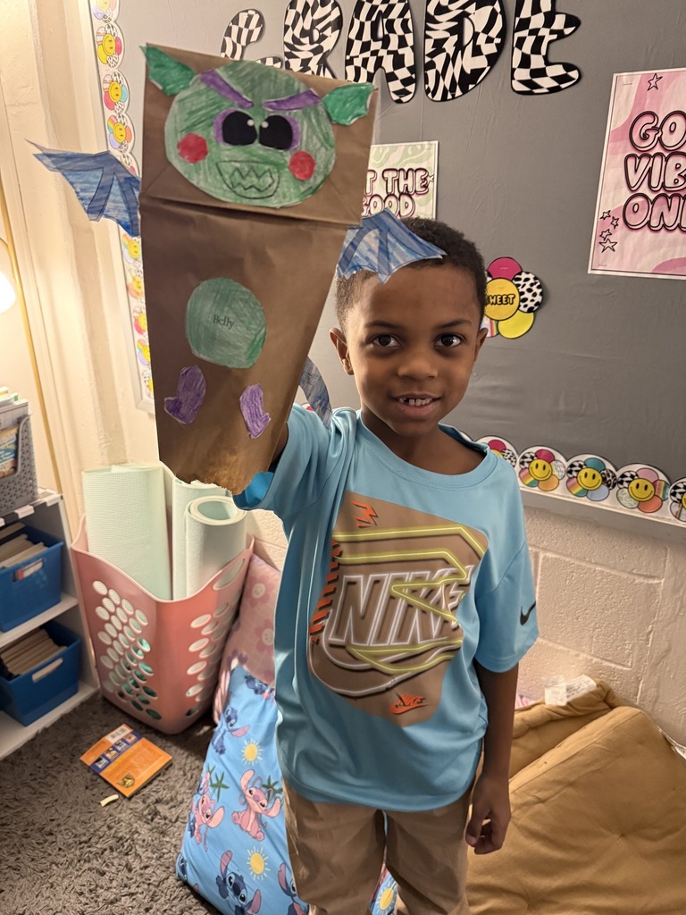 Young boy holding his dragon puppet up.