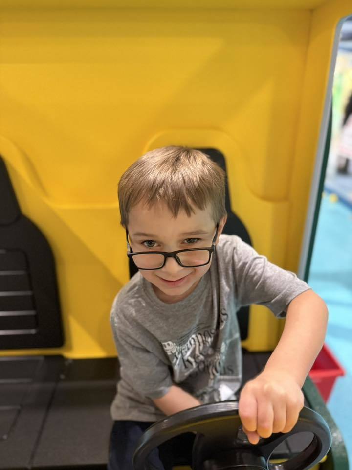 Young boy wearing glasses and play driving. 