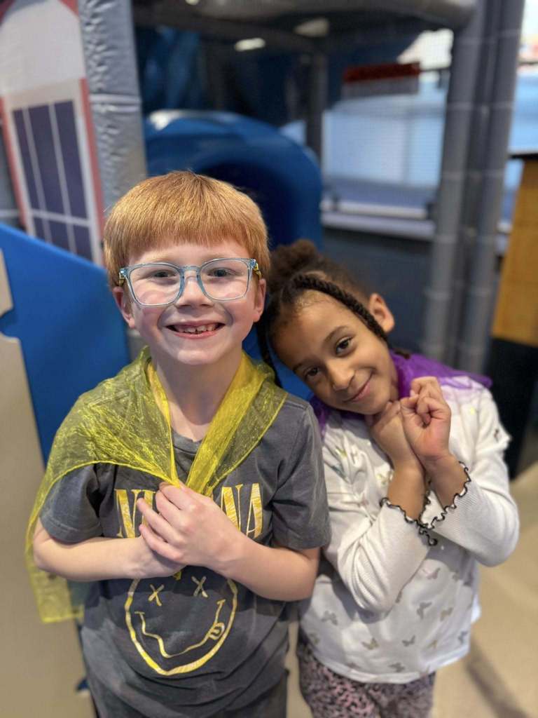 Young boy and girl wearing capes and smiling,