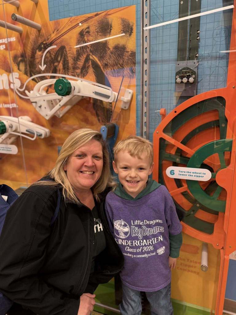 Adults and young boy in a play room smiling. 