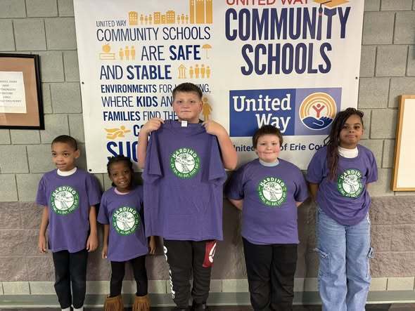 Young kids wearing and one kid holding a purple shirt. 