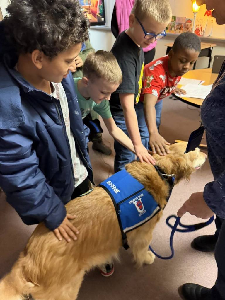Kids petting a golden retriever dog. 