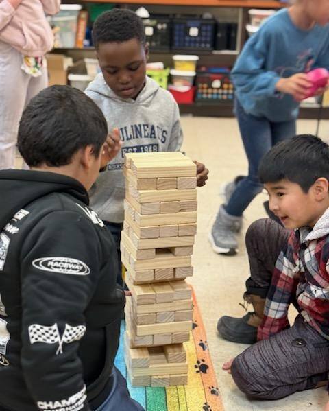 Kids playing jenga in a classroom.