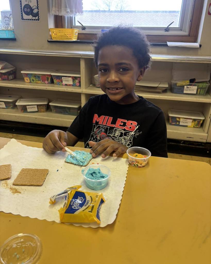 Young boy frosting a cookie and smiling. 