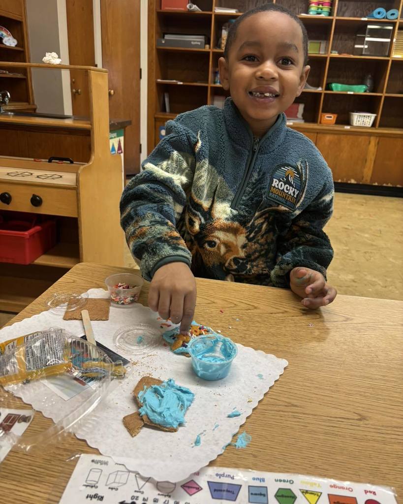 Young boy frosting a cookie and smiling. 
