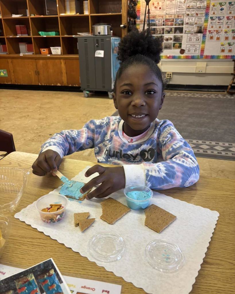 Young girl frosting a cookie and smiling. 