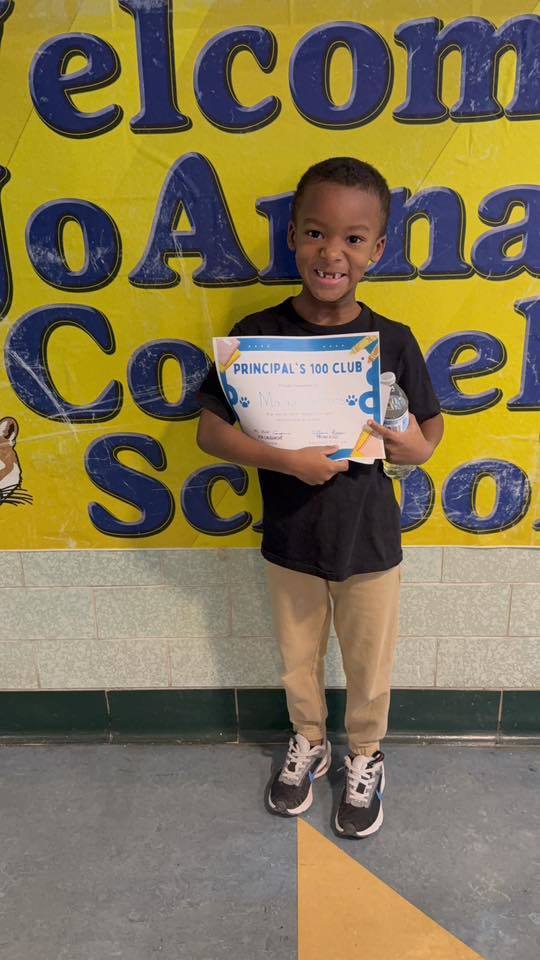 Young boy in a black shirt, holding his certificate.