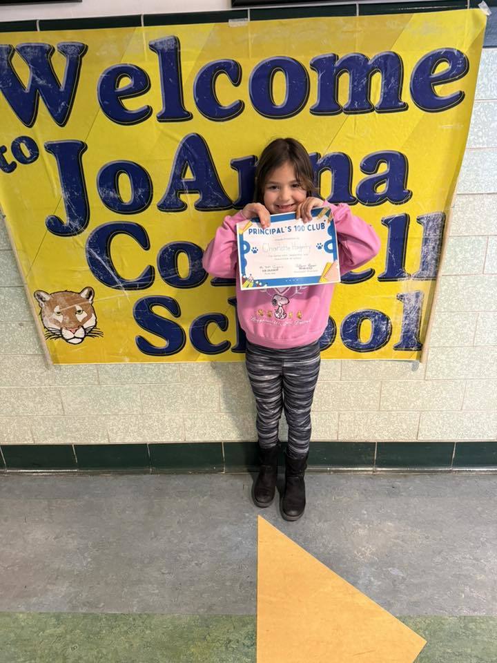 Young girl in a pink shirt, holding her certificate.