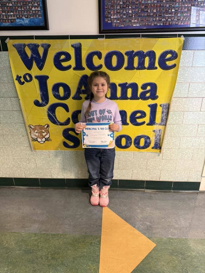 Young girl in a purple shirt holding her certificate.