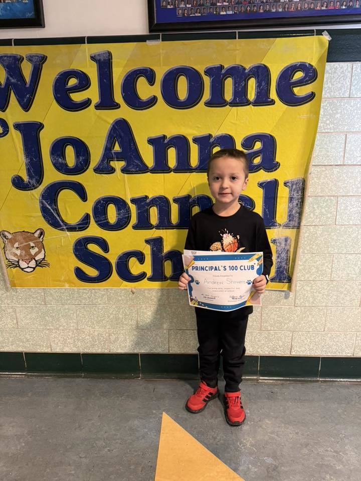 Young boy in a black shirt and black pants, holding his certificate.