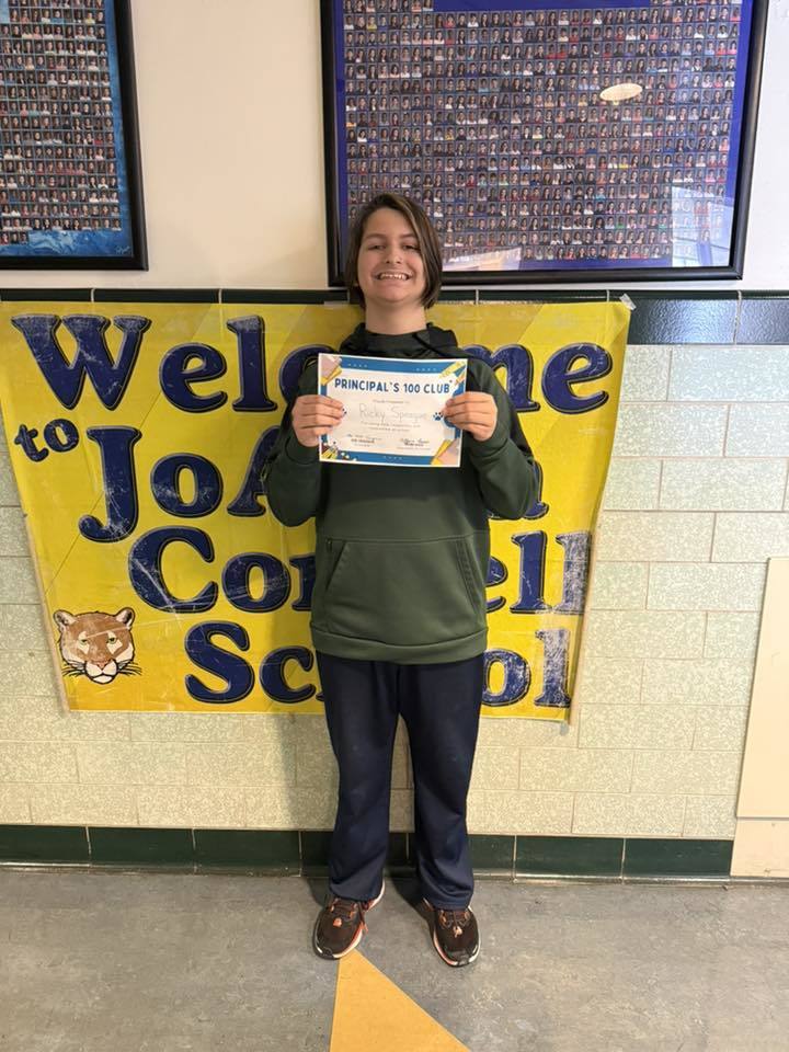 Young boy in a green hoodie holding his certificate.