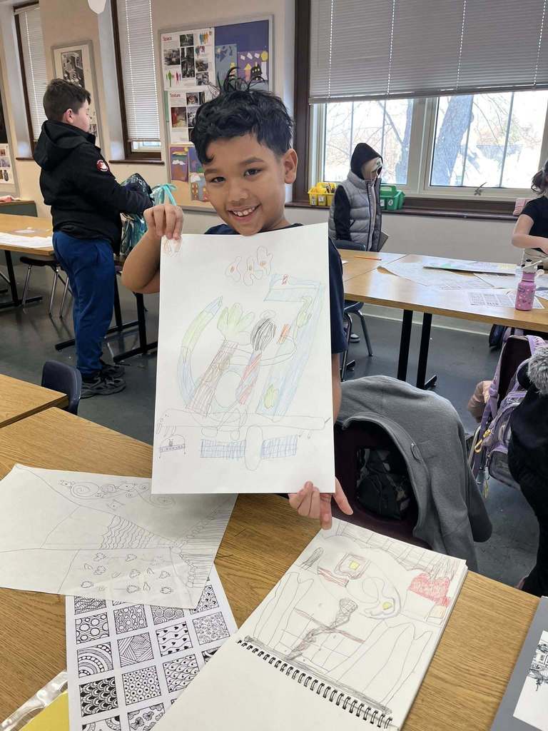 Young boy holding up her drawing.