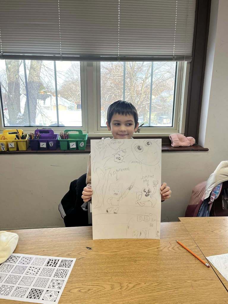 Young boy holding up his drawing. 