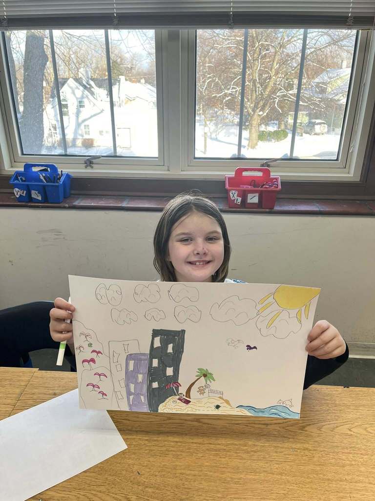 Young girl holding up her drawing.