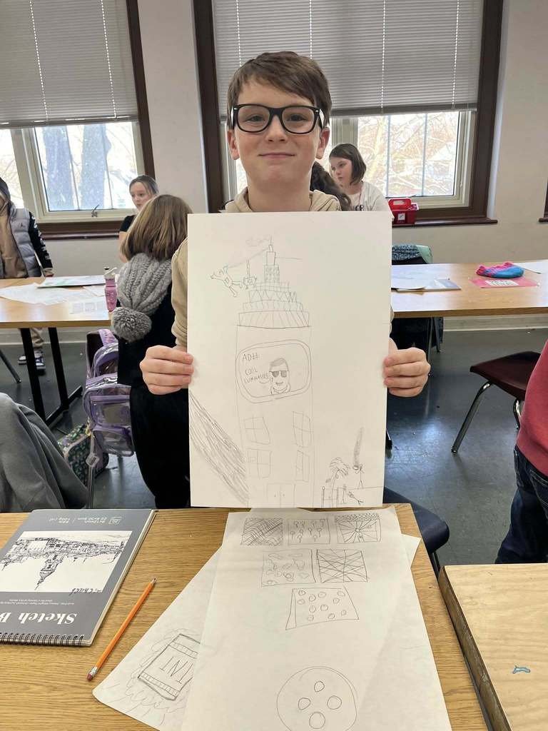 Young boy holding up her drawing.