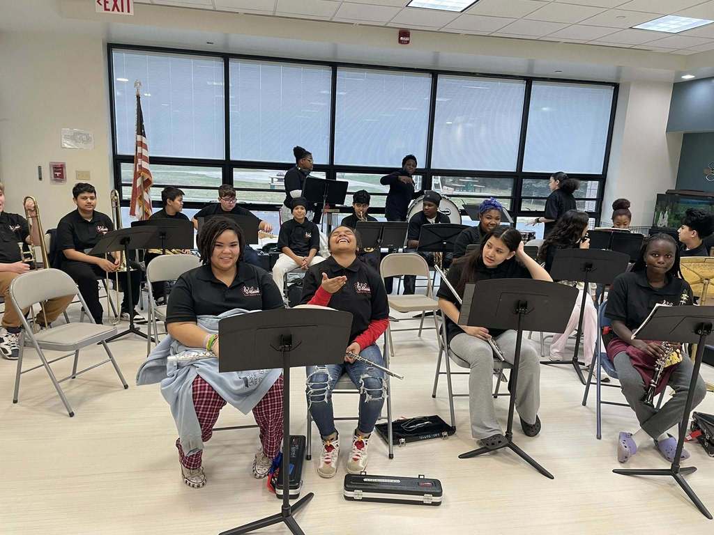 Kids holding their instruments and sitting. 