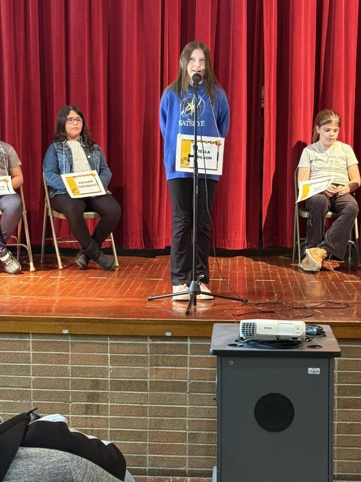 Young girl standing at a microphone on a stage.