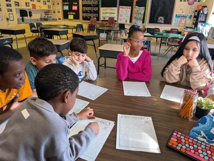 Kids in a classroom sitting and doing paper assignments.