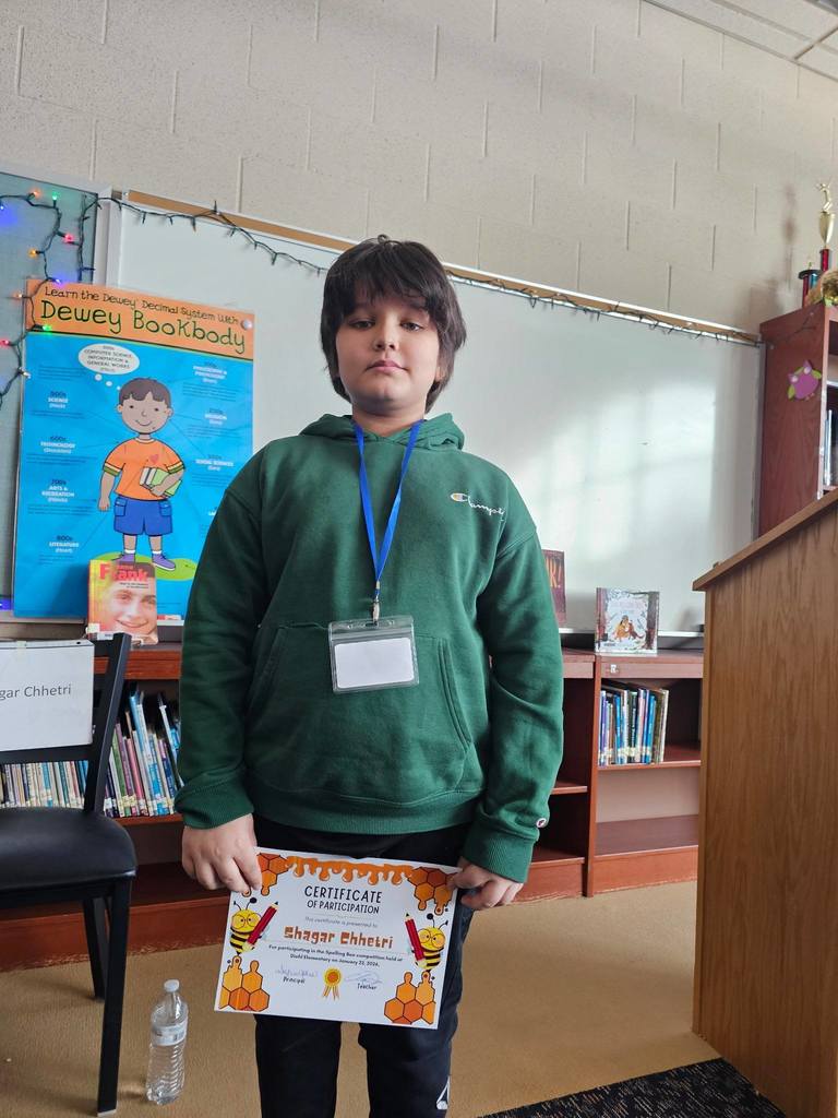 Young boy in a green hoodie holding his certificate.