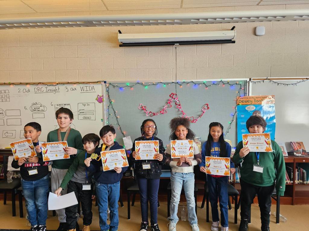 A group of kids holding their certificates in a classroom.
