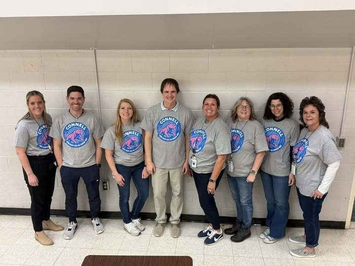 A group of adults in matching gray shirts smiling.