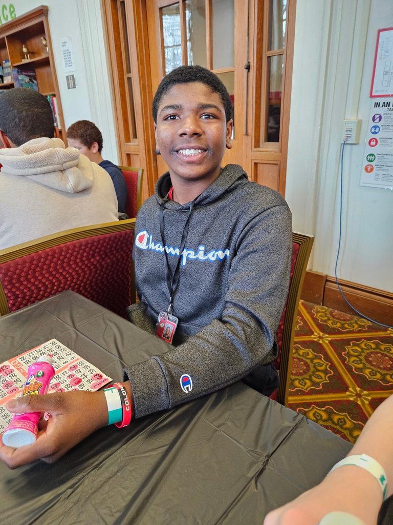 Young boy in a gray hoodie smiling while playing bingo. 