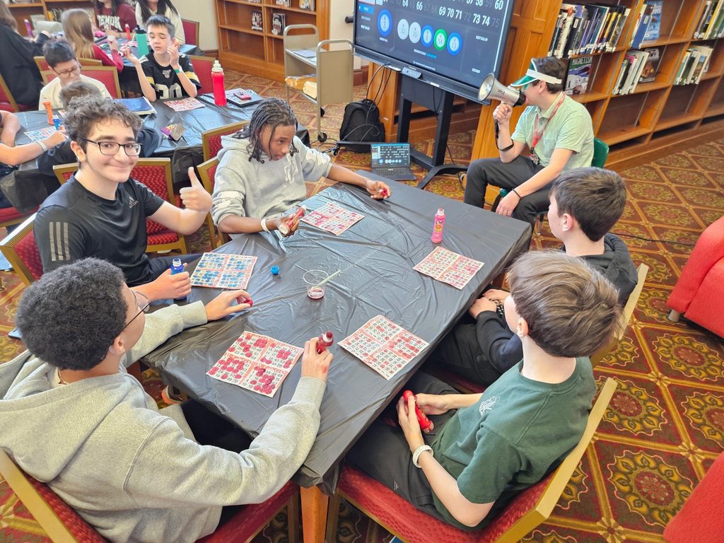 Young boys sitting at a table and playing bingo.  