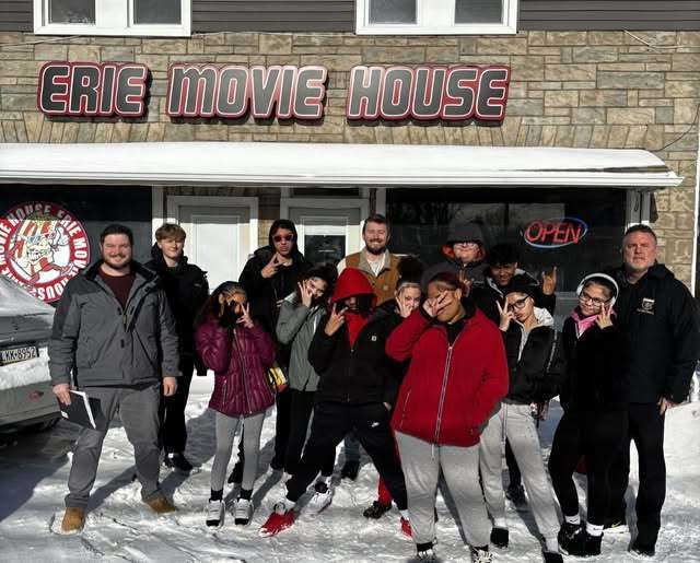 Group of people standing outside of the Erie Movie House in the snow. 