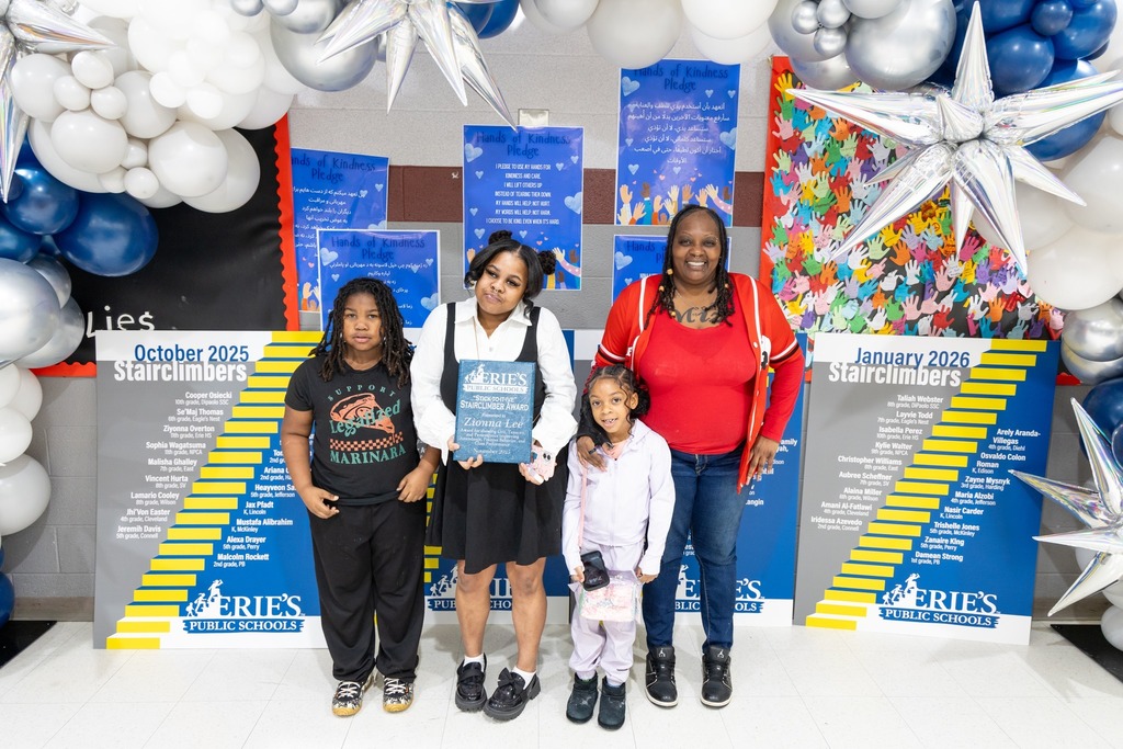 Kiids and adult smiling and one of the children is holding an award. 