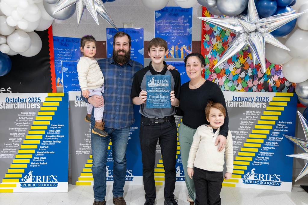 Kiids and adult smiling and one of the children is holding an award. 