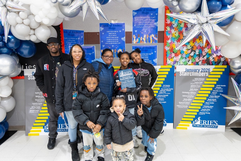 Kiids and adults smiling and one of the children is holding an award. 