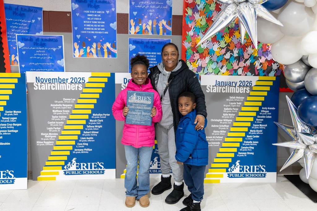 Kiids and adult smiling and one of the children is holding an award. 