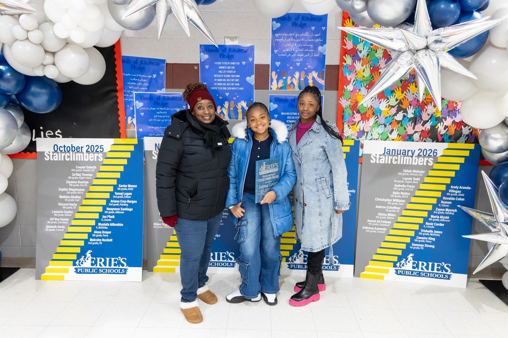 A young girl is holding an award and smiling next to two females. 