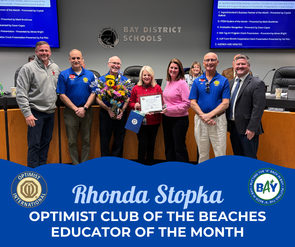 line of professionals with flowers and certificate including Optimist Club members, School Board Chair, Ms. Stopka, and Ms. Frowert
