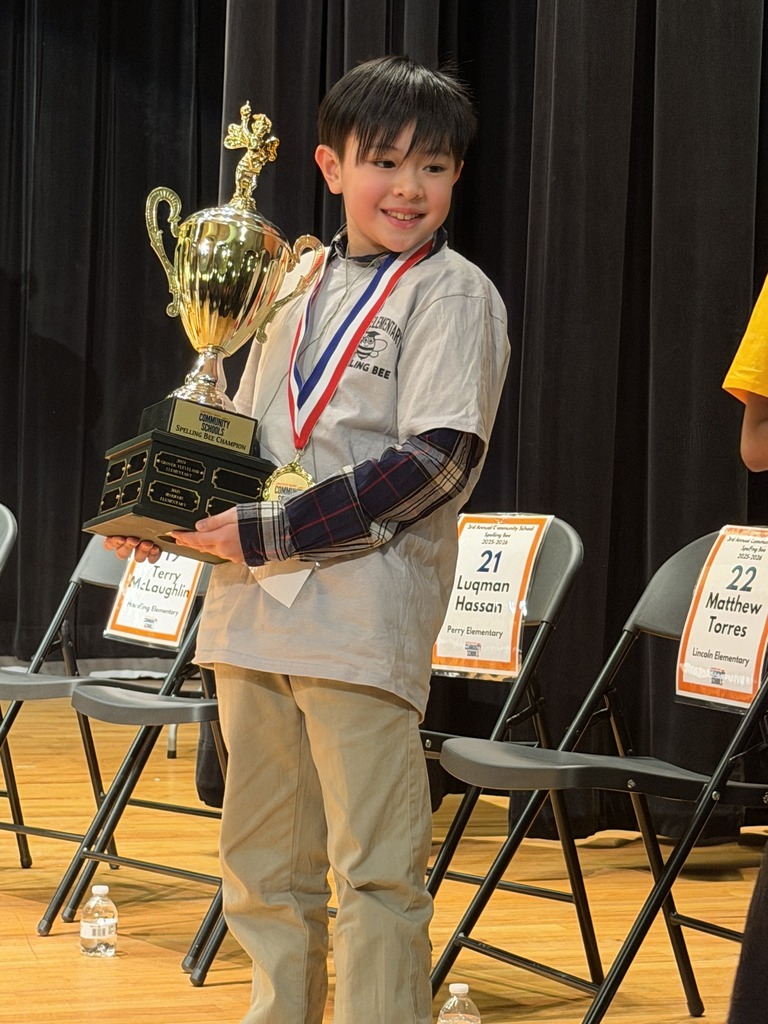 Young boy in a gray shirt holding a trophy. 