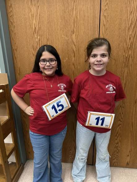 Two young girls in red shirts smiling.