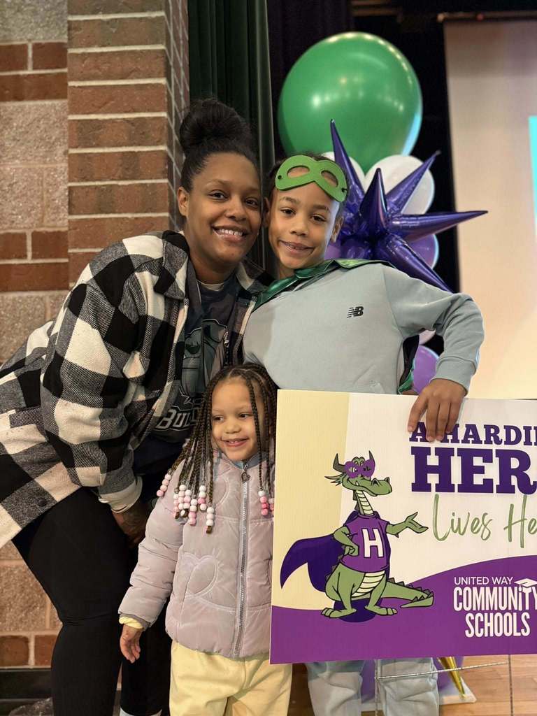 Women in a plaid shirt standing next to a young boy in a light blue top and a young girl in a purple jacket. 