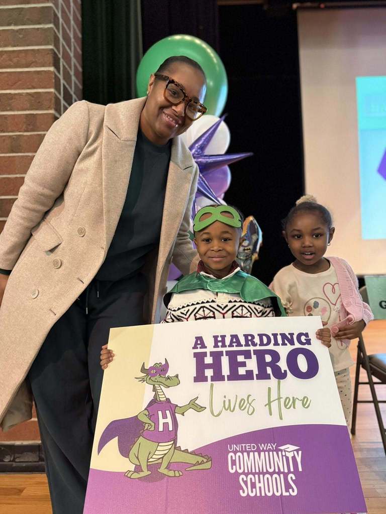 A young boy standing in between a women and young girl who is wearing pink. 