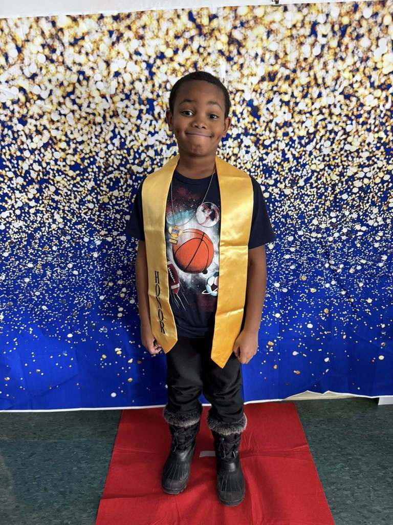 Young boy wearing a black shirt and a gold honors stole.