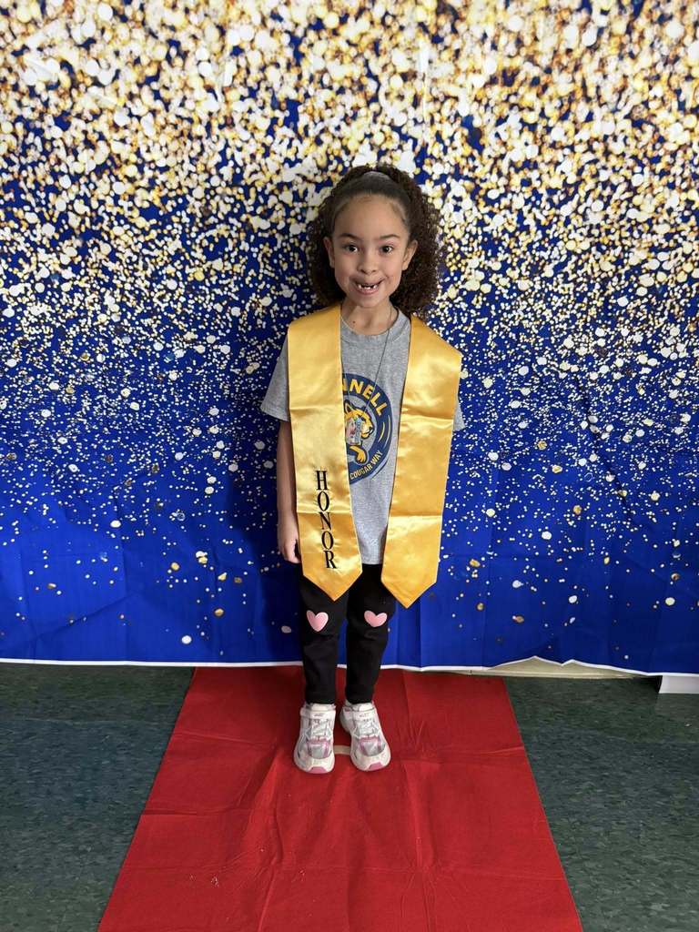 Young girl wearing a gray shirt and a gold honors stole.