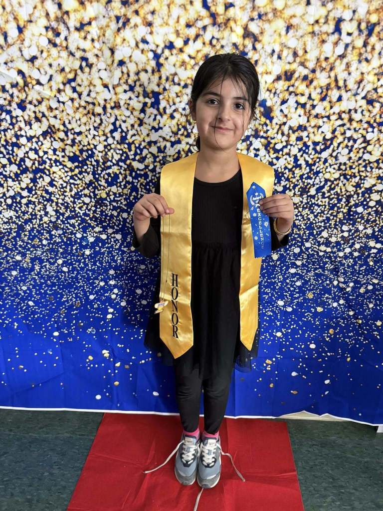Young girl wearing a black shirt and a gold honors stole.