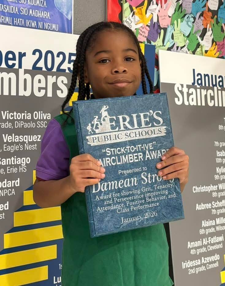 Young boy in a green shirt and is holding an award.