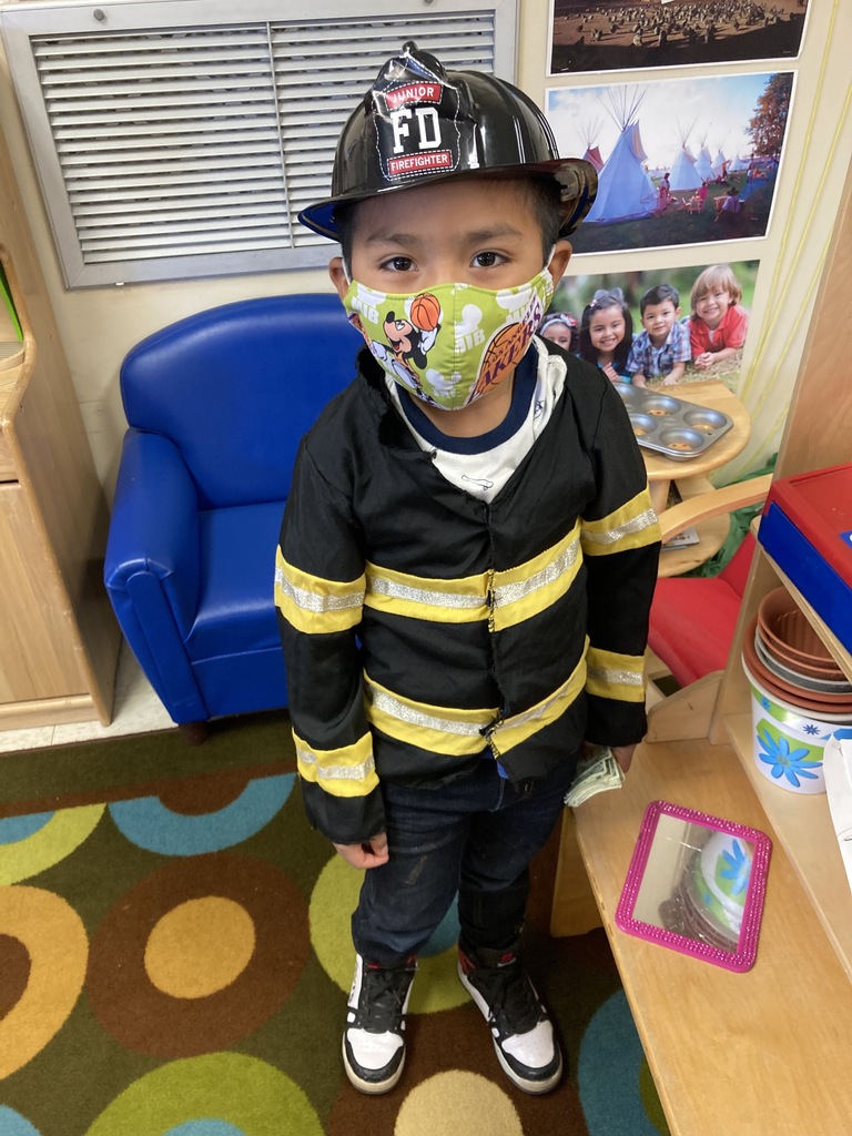 A little boy is dressed up like a fire fighter.