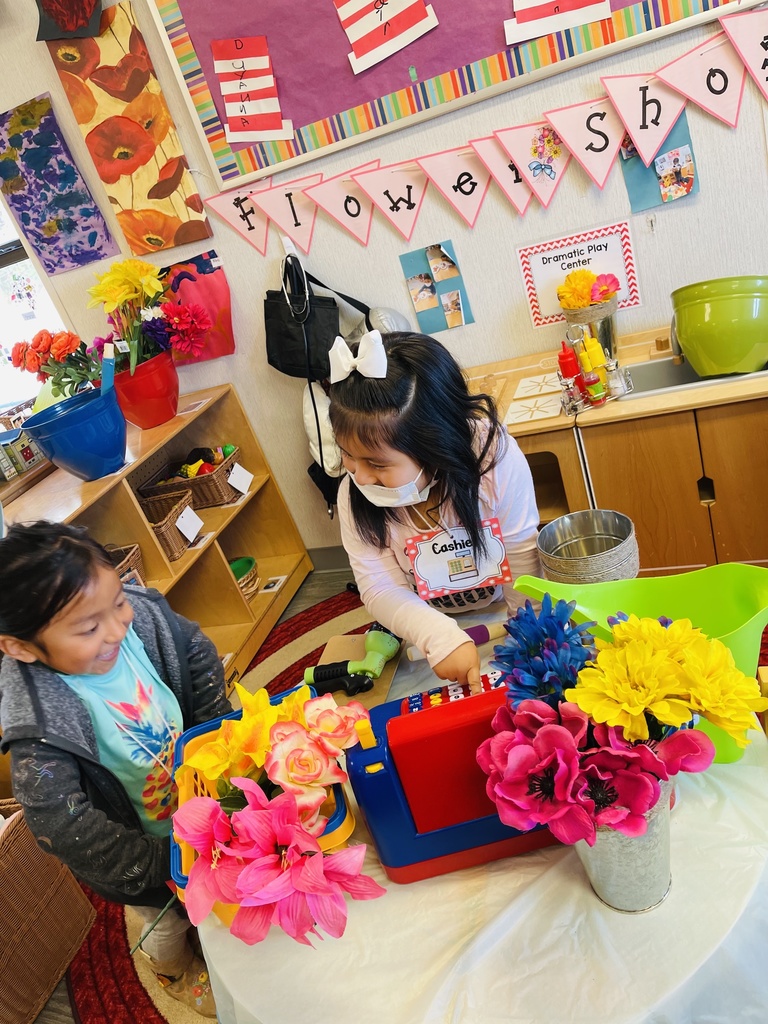 Two girls are pretending they are at a flower shop in the Dramatic Play Center.