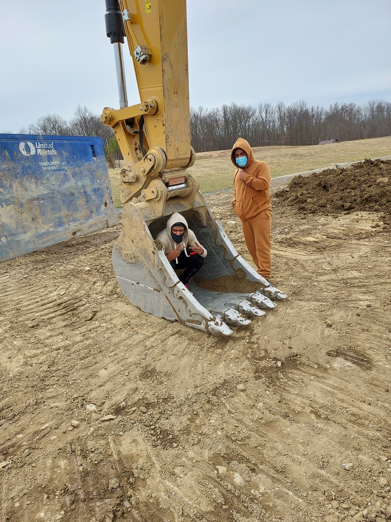 students next to construction vehicle