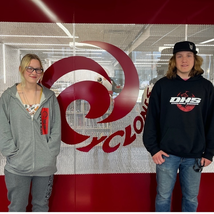 2 students in front of the Cyclone emblem