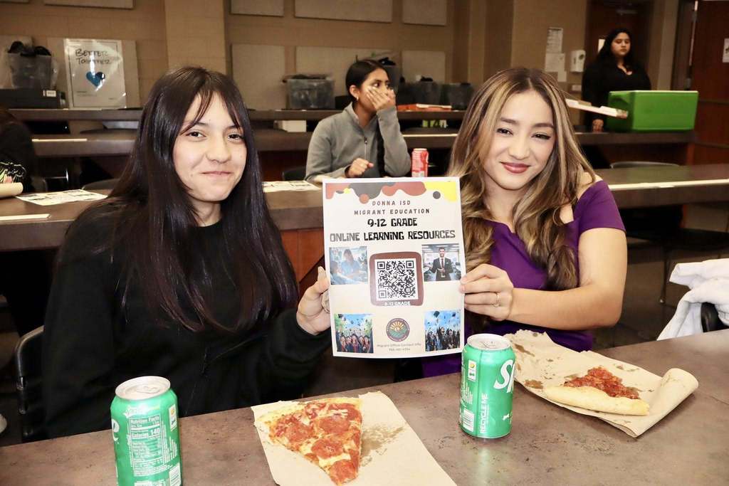 2 female students holding migrant camp flyers