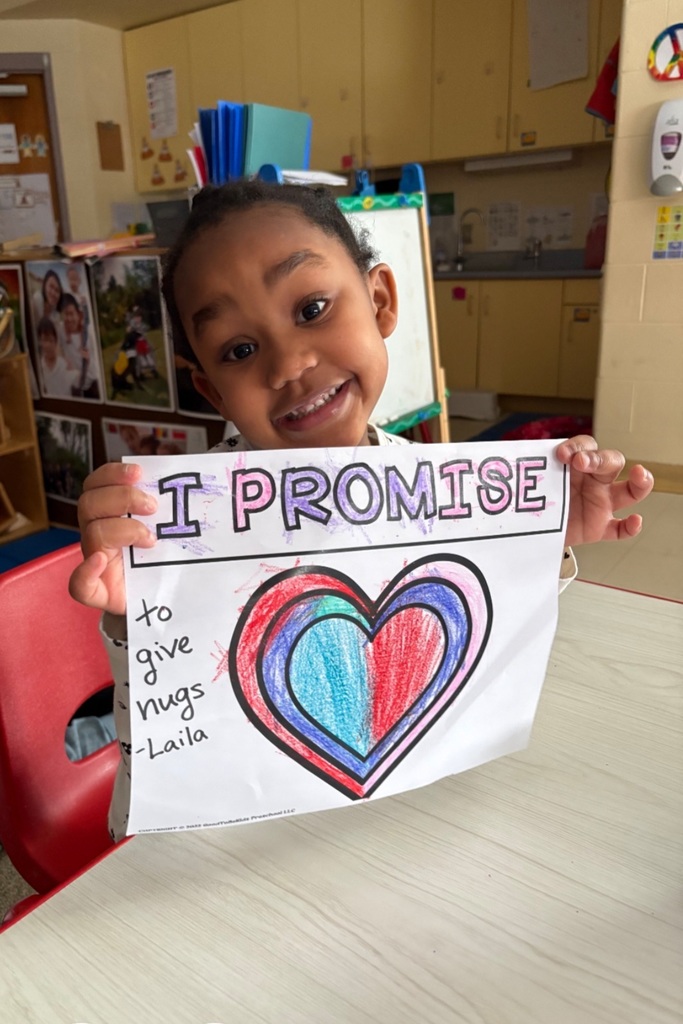 Young girl holding a paper with a colorful heart on it and it says "I promise" at the top.