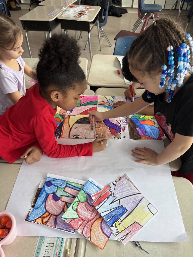 Kids at a desk coloring in a classroom.